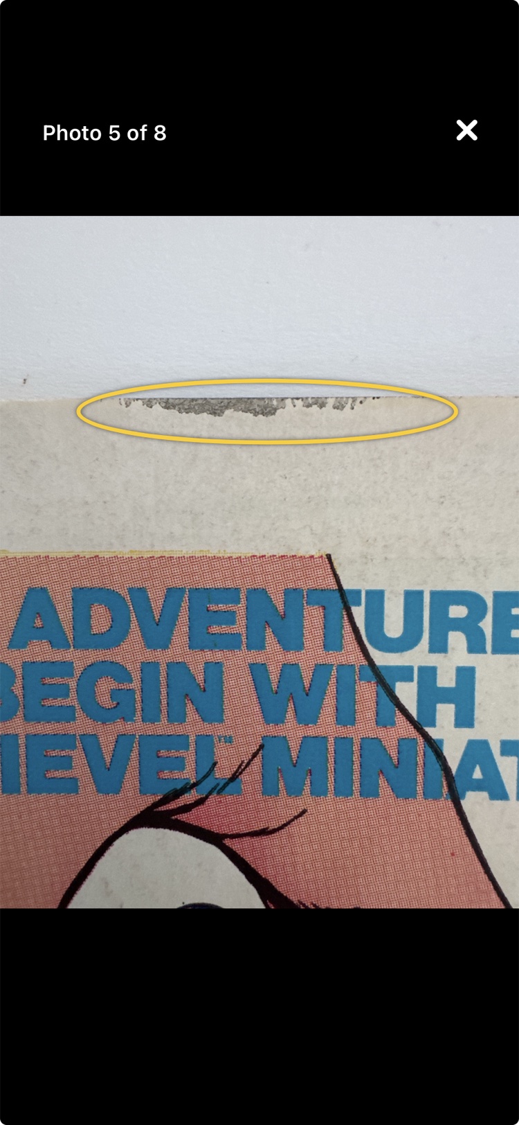 An annotated photo: a yellow ring drawn around paper loss on the back cover's top edge.